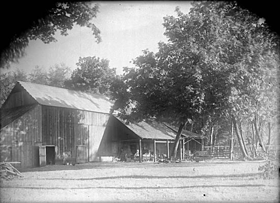 Farm buildings with carriages stored beside the building under cover