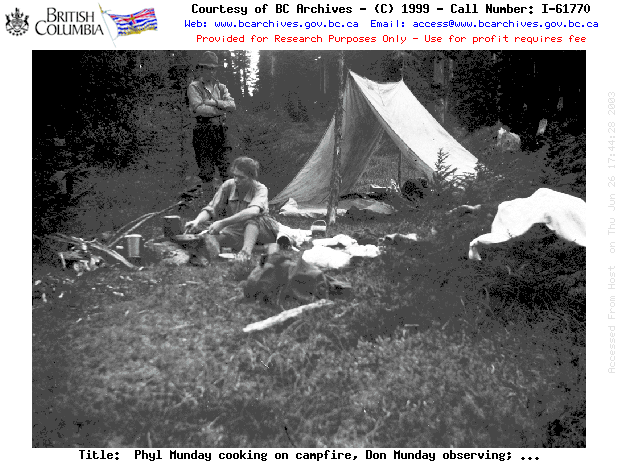 Phyl Munday cooking on campfire, Don Munday observing; on the trail, Golden Ears; box 38 "Golden Ears".